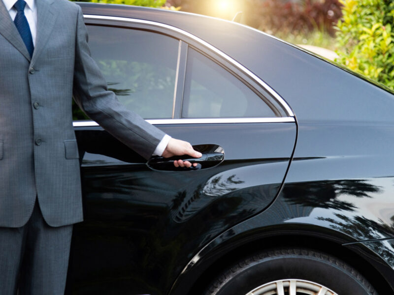 unrecognizable well dressed male chauffeur opening a car door